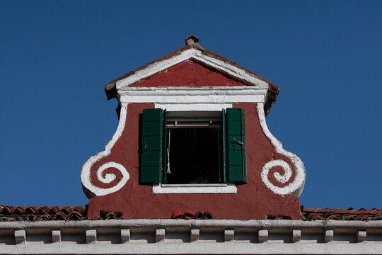 View of an atique window in an Italian house in Burano, Italy against a clear blue sky background