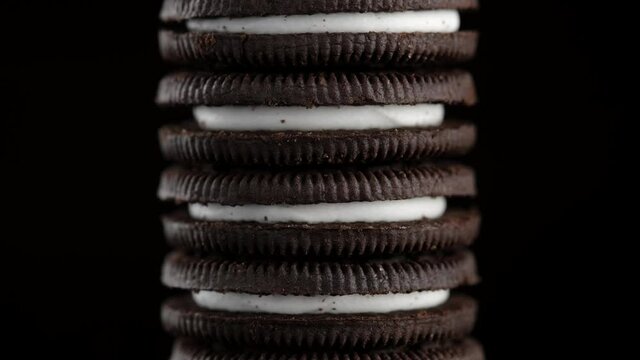 chocolate cookies with white cream close up on black background. the frame moves from bottom to top