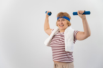 An elderly woman with a blue bandage on her head trains with dumbbells on a white background