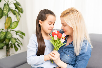 Fototapeta na wymiar Happy mother's day. Child daughter congratulates moms and gives flowers tulips