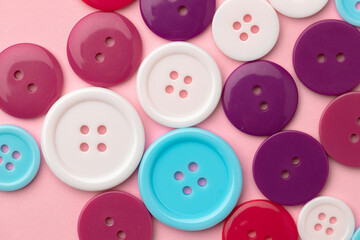 Plastic buttons on pink pastel background top view