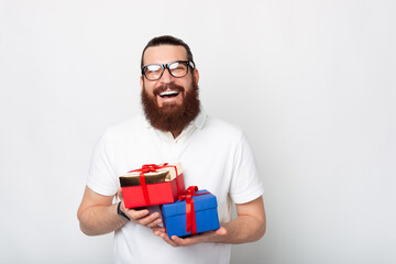 Portrait of smiling man with beard holding two gift boxes over white background