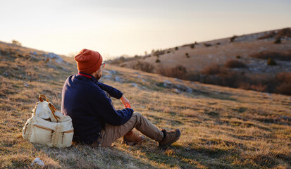 A man on top of a cliff in the spring mountains at sunset and enjoying the view of nature