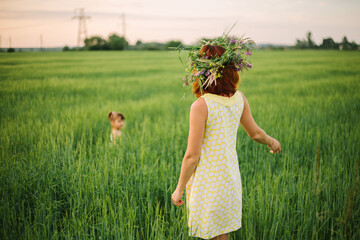 mom and daughter playing in the field. women have a wreath of wildflowers on their heads