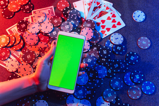 The concept of an online casino: playing cards, betting chips and a smartphone with a copy space in women's hands. Top view.