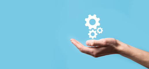 Male hand holding cog gears icon ,mechanism icon on virtual screens on blue background. Automation...