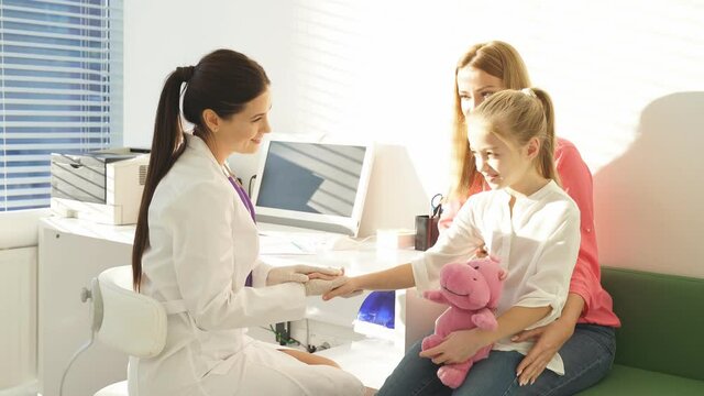 Female pediatrician welcome small kid patient and her mother at medical check up appointment, children medical health care concept.