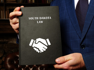 Lawyer holds SOUTH DAKOTA LAW book. South Dakota residents are subject to South Dakota state and...
