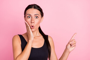 Obraz premium Photo of amazed shocked young woman point finger empty space hold hand cheek isolated on pink color background
