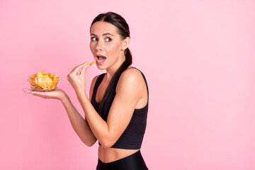Photo of doubtful hiding young lady sportswear eating potato crisps looking back empty space...