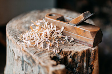 Old wooden jack plane with curly shavings. Wood shavings on old stump. Fresh curly sawdust. Wooden curls.