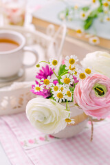 Beautiful tender blossoming of fresh cut bouquet with cup of tea nad books in background