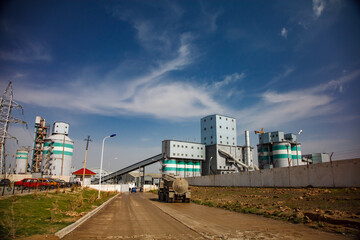 Fototapeta na wymiar Standard Cement plant. Outside Panorama view. Silos and industrial buildings. Blue sky and clouds.