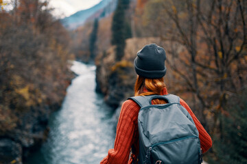 woman with backpack admires the river in the mountains nature travel