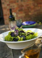 Fresh salad mix of arugula leaves, basil, and lambs lettuce. Salad bowl, healthy food. Composition in a white plate on an old wooden table