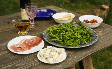 Ingredients for arugula salad, blue cheese, prosciutto, pear and caramelized nuts on an old table