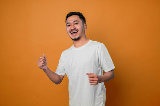 Portrait of lucky, attractive, excited, glad man with wide open mouth and raised arms looking at camera celebrating successfully passed exams, completed work, isolated on yellow background