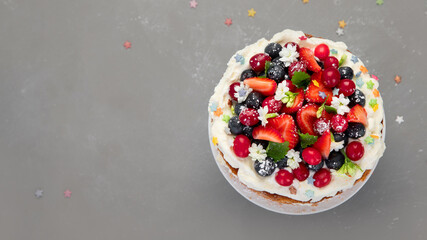 Delicious homemade cake with fresh berries and mascarpone cream on gray background.