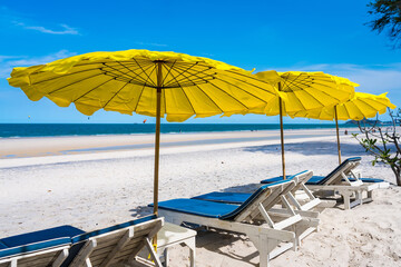 Beach chairs and Yellow Umbrellas on the beach thailand in the hot sun during the day