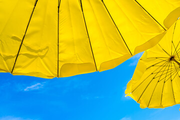 Yellow umbrella on the beach and blue sky symbolizing vacationing in summer.Thailand.