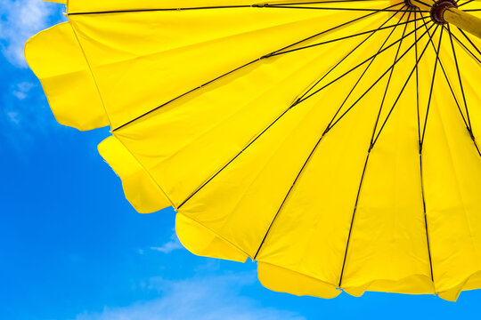 Yellow umbrella on the beach and blue sky symbolizing vacationing in summer.Thailand.