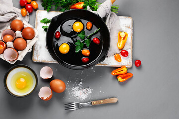 Raw eggs in pan with herbs and seasoning on gray background, prepared food for breakfast.