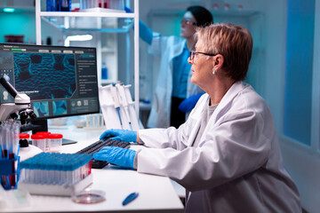 Senior scientist in chemical science laboratory study with team, test tubes, micropitette. Doctor...