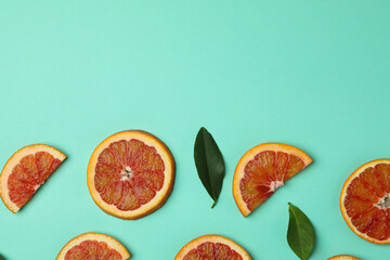 Red orange slices and leaves on mint background