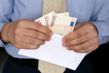 Euro banknotes in male hands close up, man in business clothes with money in white envelope....