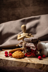 The drawing mannequin rests on a jar next to cookies and berries on a brown background close-up
