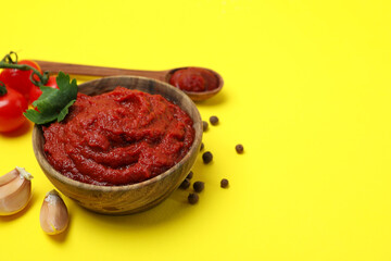 Bowl of tomato paste and ingredients on yellow background