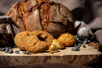 Pieces of broken biscuits lie on a wooden stump next to bread