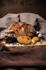 Pieces of broken biscuits lie on a wooden stump next to bread