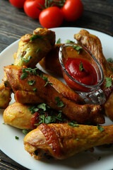 Concept of delicious eating with plate of roast chicken drumsticks on wooden background