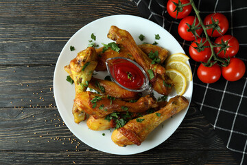 Concept of delicious eating with plate of roast chicken drumsticks on wooden background