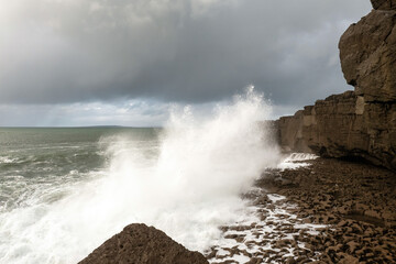 Power full ocean wave breaks on rock shore line creating big splash of water. Storm on West coast of Ireland. Power of Nature concept.