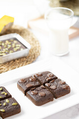 flourless pumpkin chocolate brownies set on white cafe table.