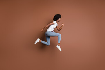 Fototapeta na wymiar Profile photo of sporty girl jump run wear white t-shirt jeans footwear isolated brown color background