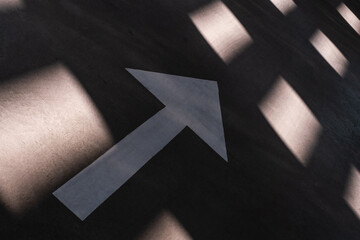 Close up of arrow sign on a concrete floor, canted angle shot.