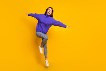Fototapeta na wymiar Photo of cute funny young woman wear purple pullover jumping high empty space isolated yellow color background