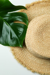 Straw hat and palm leaf on white background