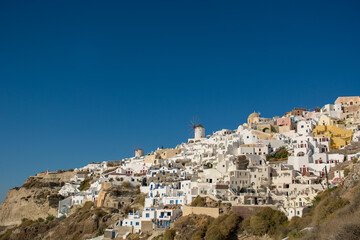 Fototapeta na wymiar Beautiful view of the famous Santorini windmills and white buildings on the cliff