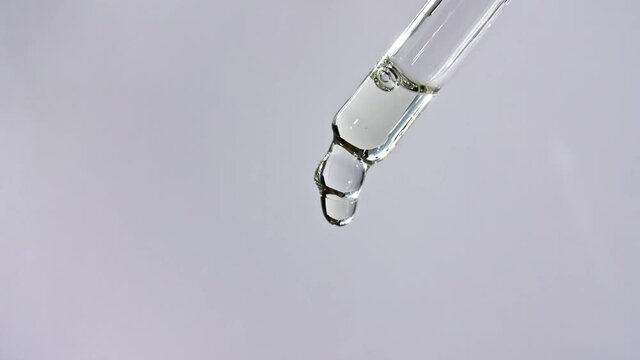Cosmetic pipette with drops of oil close up on gray background. High quality 4k footage