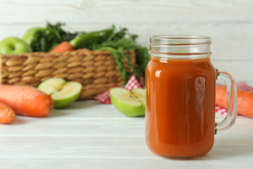 Jar of apple - carrot juice and ingredients on white wooden background