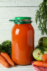 Jar of apple - carrot juice and ingredients on white wooden background