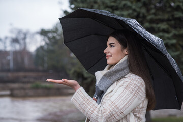 Portrait of a brunette girl with an umbrella walking in cloudy and rainy weather
