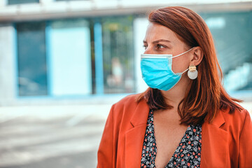 Business lady with foxy hairwearing protection face mask against coronavirus MERS-Cov, Novel...