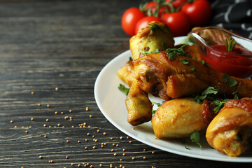 Concept of delicious eating with plate of roast chicken drumsticks on wooden background