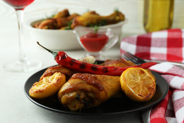 Concept of delicious eating with roast chicken drumsticks on white textured table