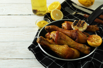 Concept of delicious eating with pan of roast chicken drumsticks on white wooden table
